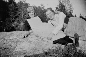 Svart-hvitt fotografi av to damer som ligger på en stein