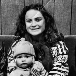 Kvinne holder et lite barn på fanget i et historisk svart-hvitt fotografi.