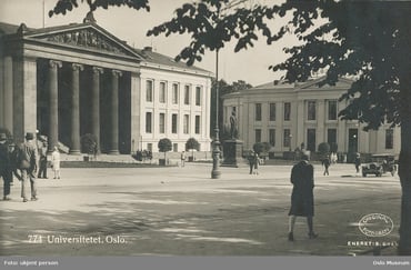 Svart-hvitt bilde av Universitetetsplassen i Oslo med forbipasserende..