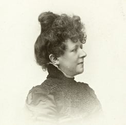 Svart-hvitt portrettbilde av kvinne i profil med hårtopp og 1890-talls kjole