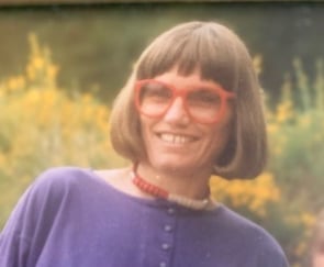 Blid dame med brun bob og røde briller