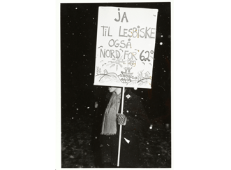 Kvinne i snødriv holdende og delvis skjult bak plakat: Ja til lesbiske også nord for 62 grader.