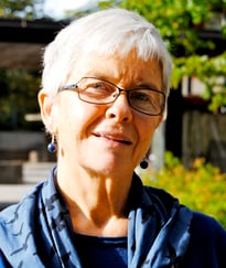 Fargeportrett av en kvinne med briller utendørs.
