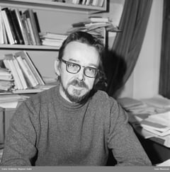 Rufsete professor-mann med skjegg og briller på kontor med bøker og papirer