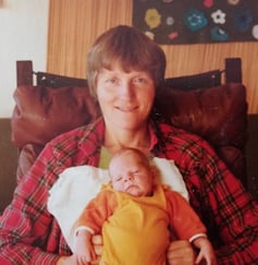 Farget fotografi av kvinne med kort hår med baby på fanget.