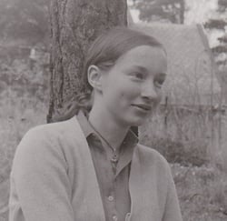 Svart-hvitt bilde av kvinne sittende foran et tre.