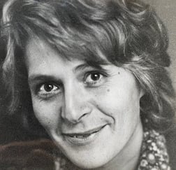 Svart-hvitt bilde av kvinne som smiler.