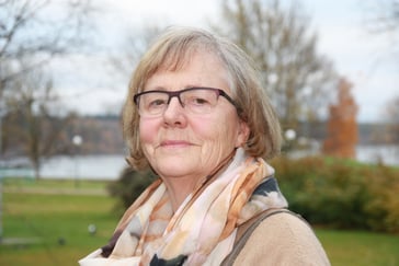 Portrett av kvinne med brilller og skjerf rundt halsen. 