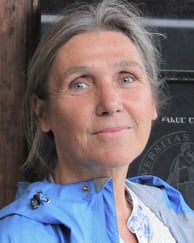 Farget bilde av kvinne med oppsatt hår og blå jakke 
