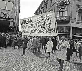Demonstrasjonstog i bygate med banner som krever «Likelønn også i praksis».