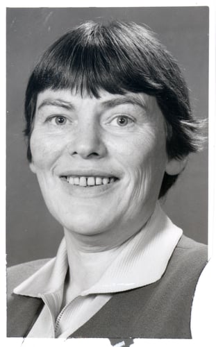 Svart-hvitt portrettfoto av en person med kort hår, sett mot en nøytral bakgrunn.