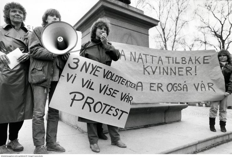Gruppebilde 4 kvinner. Appell i megafon. Plakat med "3 nye voldtekter  - vi vil vise vår PROTEST" og banner med "Ta natta tilbake kvinner! Natta er også vår". 