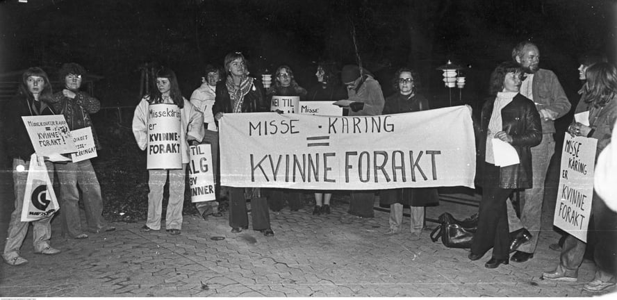 Gruppebilde punktdemonstrasjon i mørket, plakater og banner med "Misse-kåring = kvinneforakt".