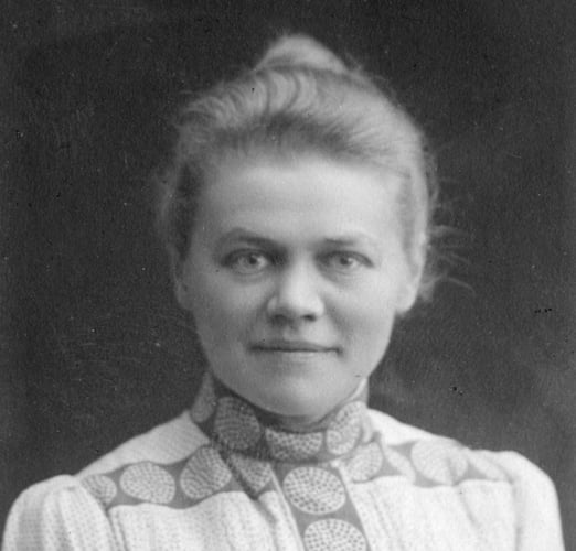 Historisk portrettfotografi av en person med oppsatt hår og mønstret krage.
