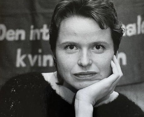 Nærbilde i svart-hvitt bilde av ung kvinne foran en banner