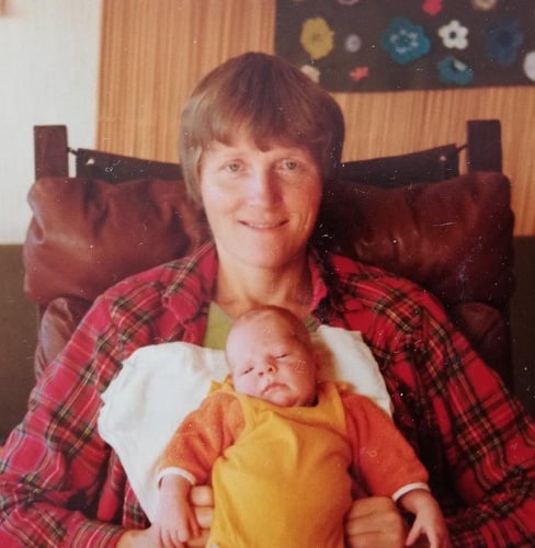 Farget fotografi av kvinne med kort hår med baby på fanget.