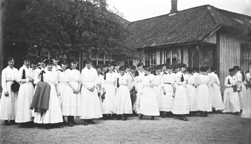 Svart-hvitt bilde av gruppe kvinner med hvite kjoler.