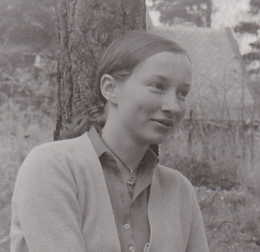 Svart-hvitt bilde av kvinne sittende foran et tre.