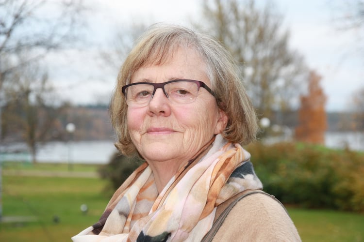 Portrett av kvinne med brilller og skjerf rundt halsen. 