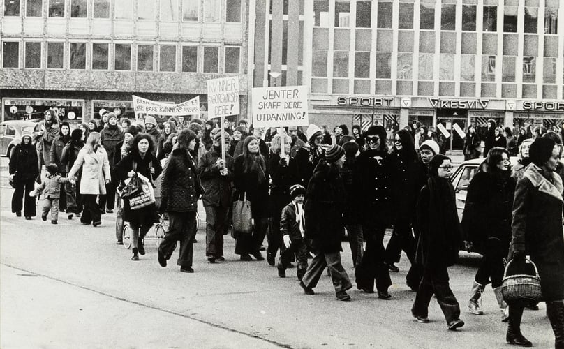 8. mars demonstrasjon, bygate i Trondheim. Paroler: "Kvinner, fagorganiser dere!", "Jenter, skaff dere utdanning!", "Barn… er ikke bare kvinnens ansvar".