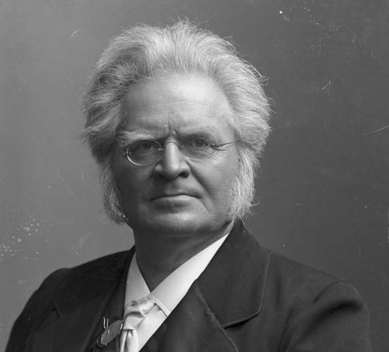 Svart-hvitt portrettfotografi av en mann med briller og karakteristisk hårfrisyre.
