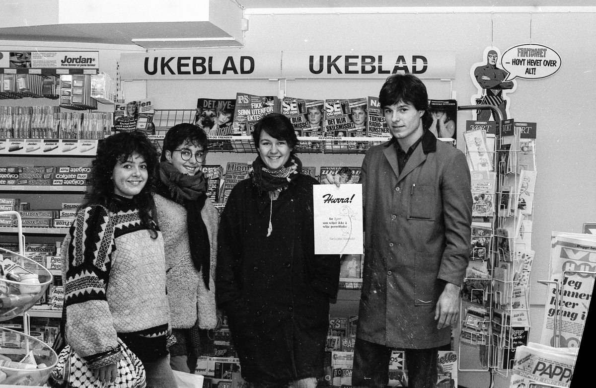 Gruppebilde 3 jenter og ein mannleg butikkekspedit&oslash;r med diplom framfor vekebladhylle i daglegvarebutikk. 