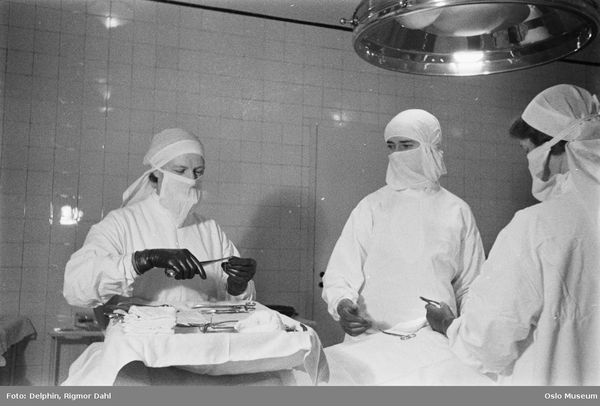 Operasjon p&aring; R&oslash;de Kors Klinikk. Tre hvitkledde personer med munnbind i gang med kirurgisk inngrep. 