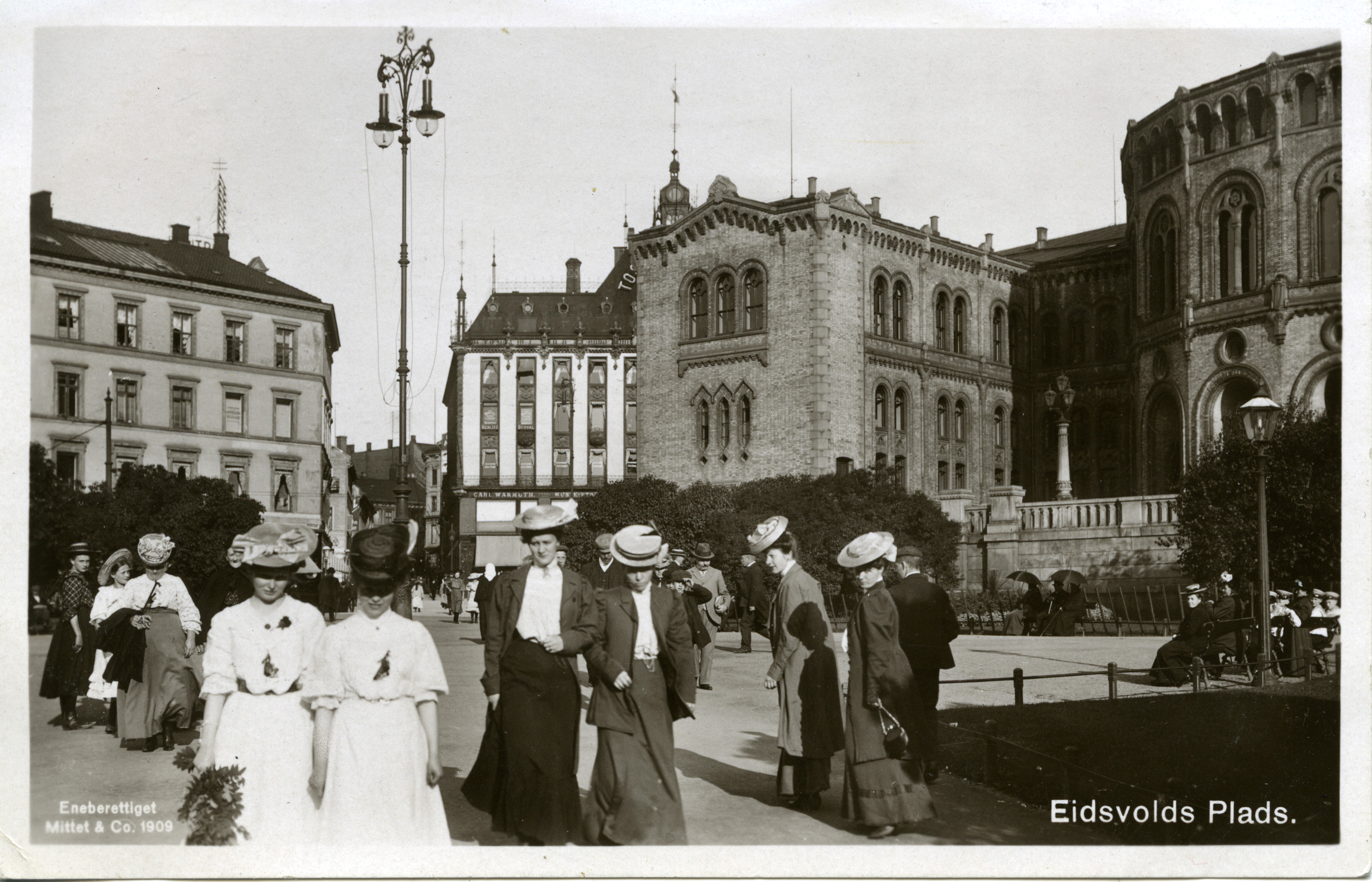 Bilde av kvinner i kjole og hatt på Eidsvolls plass utenfor Stortinget.