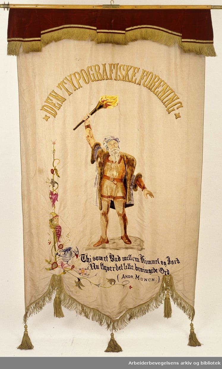 Fane for Den typografiske forening. Illustrert med maleri av skjeggete mann med fakkel (Gutenberg) og teksten "Den typografiske forening. Thi som et bud mellem Himmel og Jord. Nu flyver det lette, bevingede Ord (Andr. Munch)".